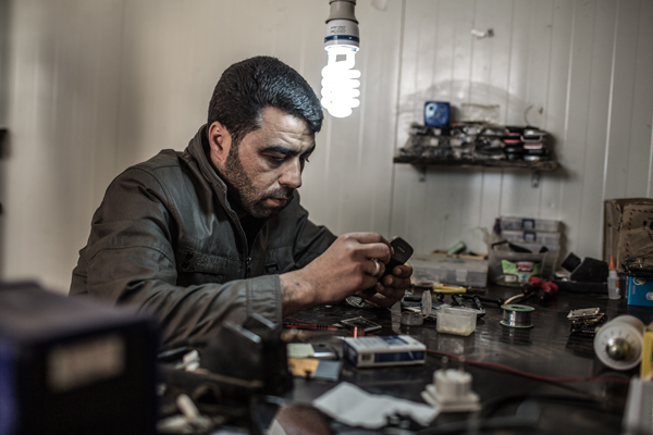 Syrian refugee Maamoun Wadi fixes mobile phones at his shop at the Zaatari camp in this still from the documentary 'District Zero' (Photo courtesy of Oxfam)